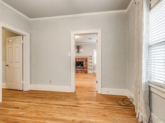 empty room featuring crown molding, a fireplace, and light hardwood / wood-style flooring