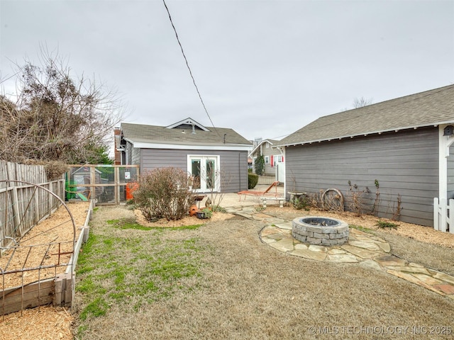 back of property with french doors, a yard, and an outdoor fire pit