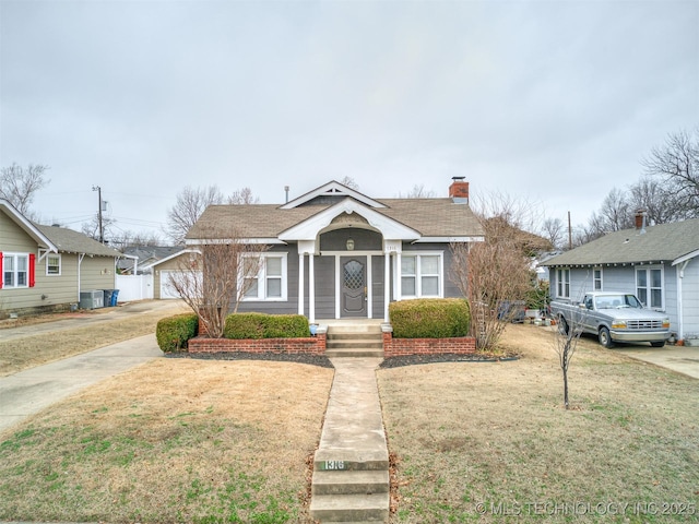 bungalow-style house with cooling unit and a front lawn