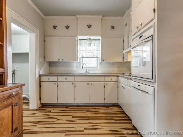 kitchen featuring white appliances, ornamental molding, and white cabinets