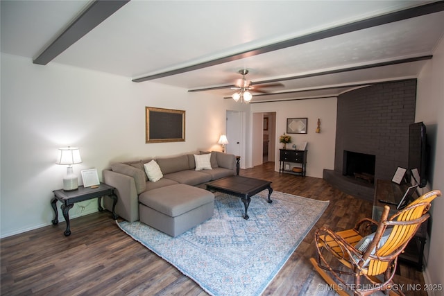 living room with a brick fireplace, dark wood-type flooring, beamed ceiling, and ceiling fan