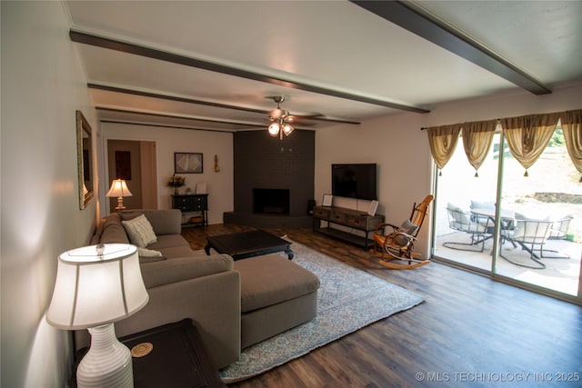 living room featuring hardwood / wood-style flooring, ceiling fan, a large fireplace, and beam ceiling