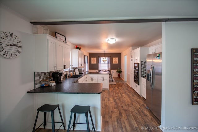 kitchen with sink, stainless steel fridge, a kitchen breakfast bar, white cabinets, and kitchen peninsula