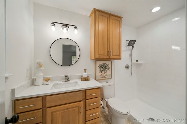 bathroom featuring vanity, toilet, and a tile shower