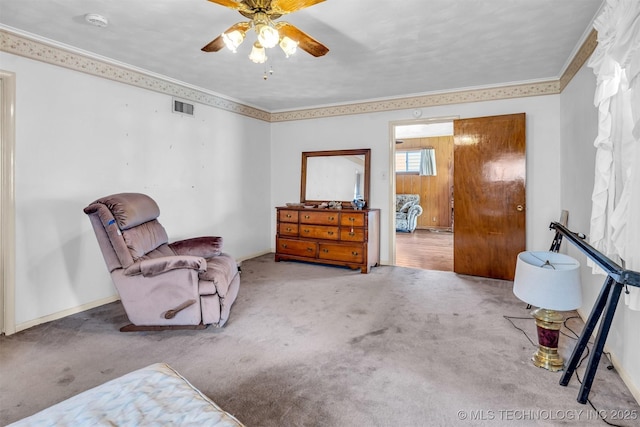 sitting room with ceiling fan, ornamental molding, and carpet floors