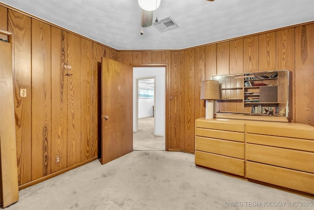 carpeted bedroom featuring ceiling fan and wooden walls