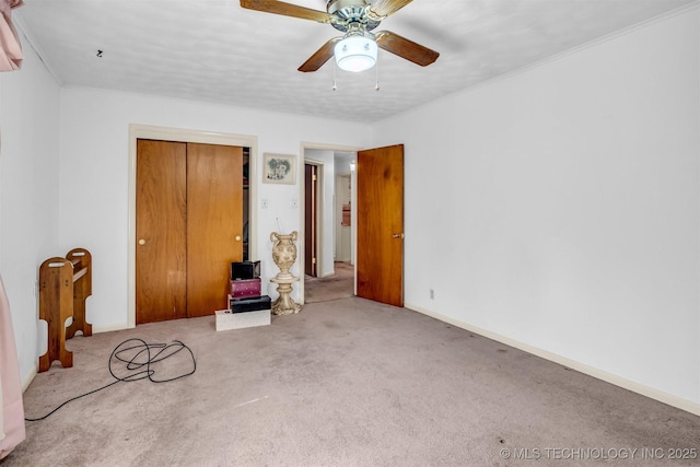 unfurnished bedroom featuring ornamental molding, light colored carpet, ceiling fan, and a closet