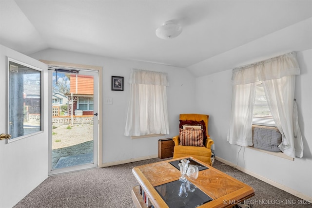 living area featuring vaulted ceiling, carpet, and a wealth of natural light