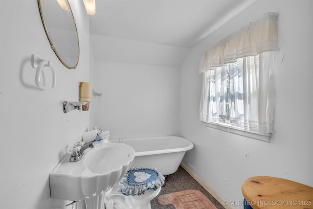 bathroom with lofted ceiling, sink, and a tub