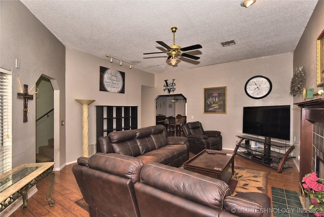 living room with ceiling fan, wood-type flooring, rail lighting, and a textured ceiling