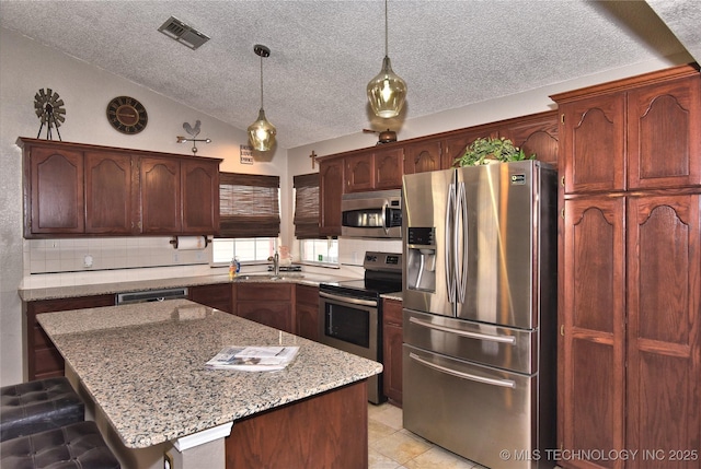 kitchen featuring sink, light stone counters, a center island, appliances with stainless steel finishes, and pendant lighting