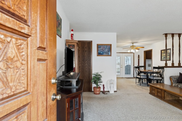 living room with french doors, ceiling fan, light carpet, and a textured ceiling