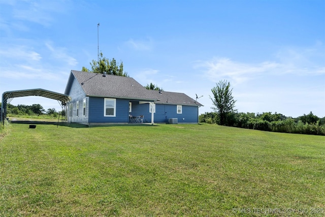 back of property with central AC, a carport, and a yard