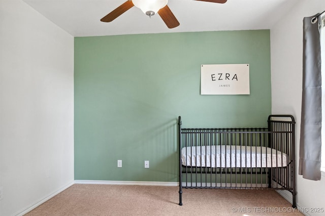 unfurnished bedroom featuring a crib, carpet, and ceiling fan