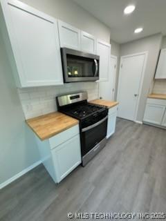 kitchen featuring stainless steel appliances, butcher block counters, white cabinets, and light hardwood / wood-style flooring