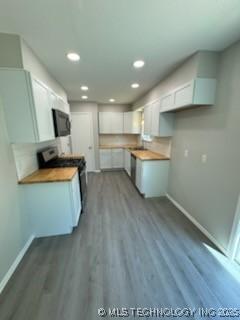 kitchen with hardwood / wood-style flooring, wood counters, stainless steel electric range, and white cabinets