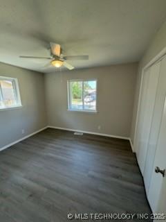 unfurnished bedroom featuring dark wood-type flooring, a closet, and ceiling fan