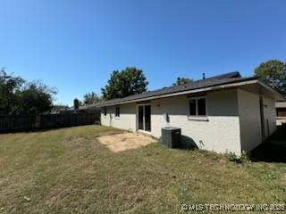 back of house featuring central AC unit and a lawn