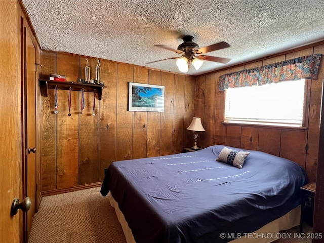 4 Canadian Dr, Burneyville, OK 73430 - carpeted bedroom featuring a textured ceiling, wood walls, and a ceiling fan
