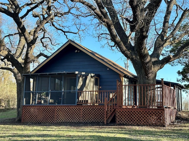 back of house featuring a wooden deck, a yard, and a sunroom