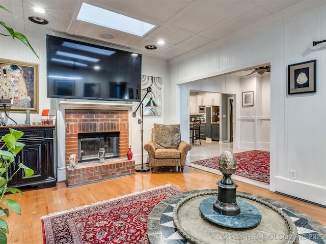 8918 S Lakewood Ave, Tulsa, OK 74137 - living area featuring wood finished floors, a fireplace, ornamental molding, a skylight, and a decorative wall