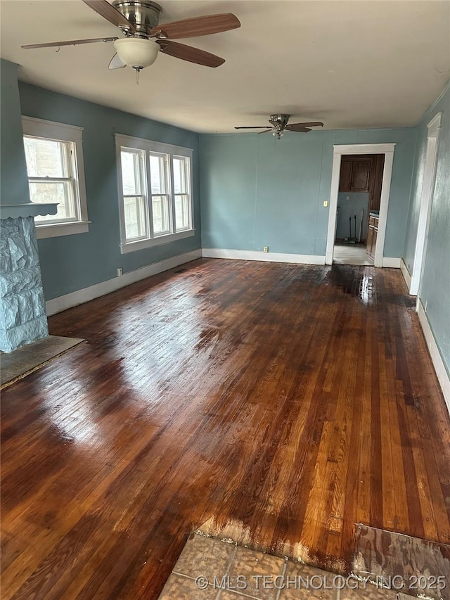 unfurnished living room with dark hardwood / wood-style floors and ceiling fan