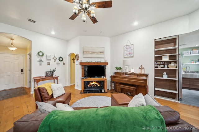 living room with sink, light hardwood / wood-style flooring, and ceiling fan