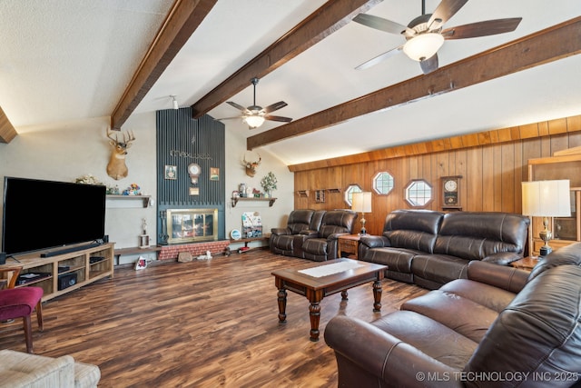 living room featuring vaulted ceiling with beams, hardwood / wood-style flooring, wooden walls, and ceiling fan