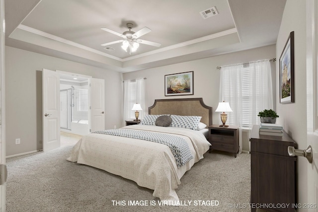 carpeted bedroom featuring multiple windows, ornamental molding, connected bathroom, and a tray ceiling