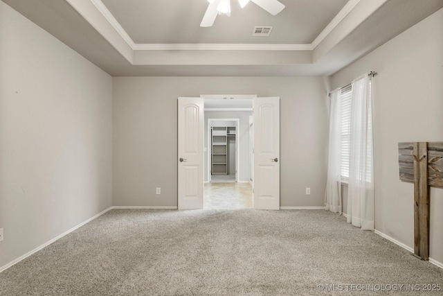 carpeted spare room with ornamental molding, a raised ceiling, and ceiling fan