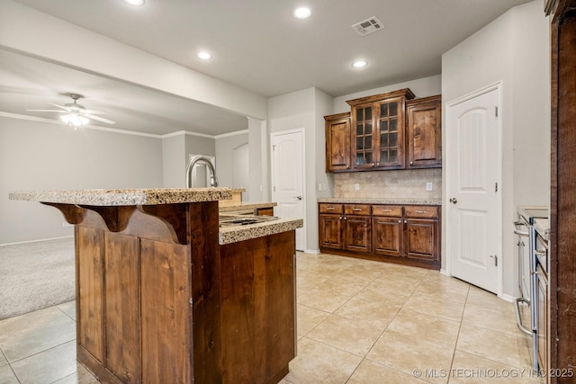 kitchen featuring a kitchen island with sink, a breakfast bar area, tasteful backsplash, and light tile patterned flooring