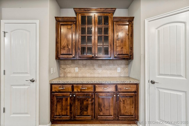 kitchen with tasteful backsplash, light stone countertops, and dark brown cabinetry