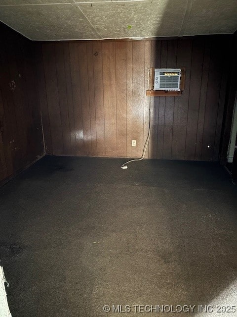 basement featuring carpet, a wall unit AC, and wood walls