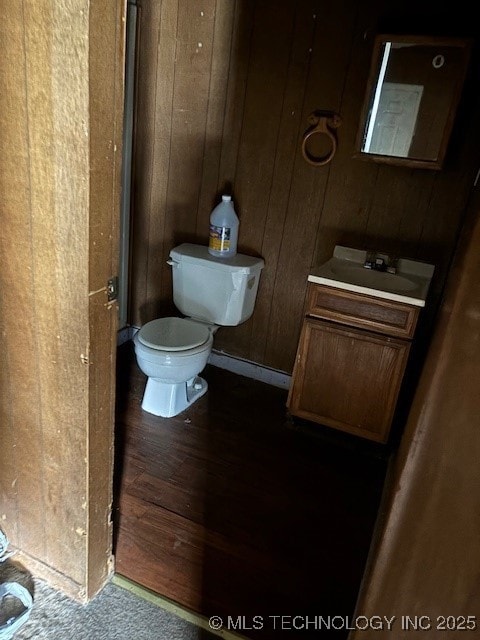 bathroom featuring vanity, toilet, and wood walls