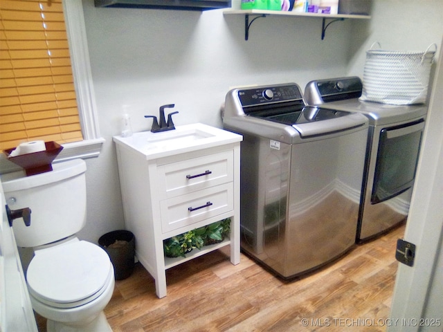 washroom featuring sink, washing machine and dryer, and light hardwood / wood-style flooring