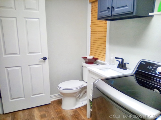 bathroom with hardwood / wood-style floors, washer / dryer, sink, and toilet