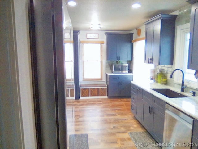 kitchen with stainless steel appliances, tasteful backsplash, sink, and light hardwood / wood-style floors