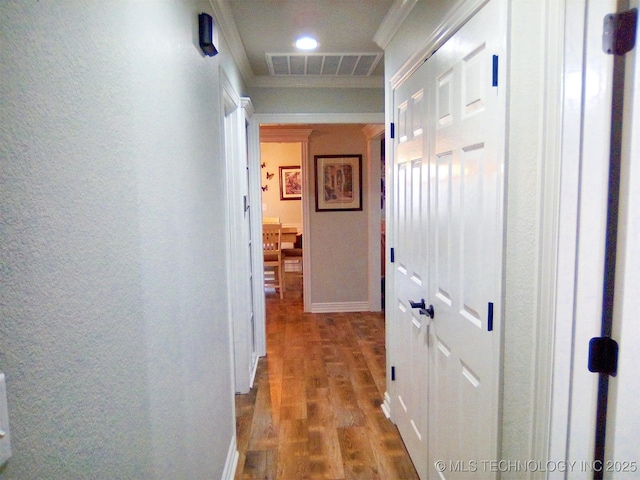 corridor with hardwood / wood-style flooring and ornamental molding