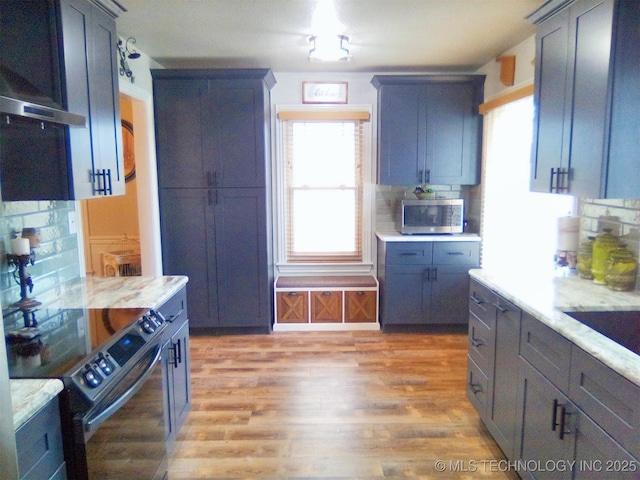 kitchen featuring tasteful backsplash, light stone countertops, electric range, and light hardwood / wood-style floors