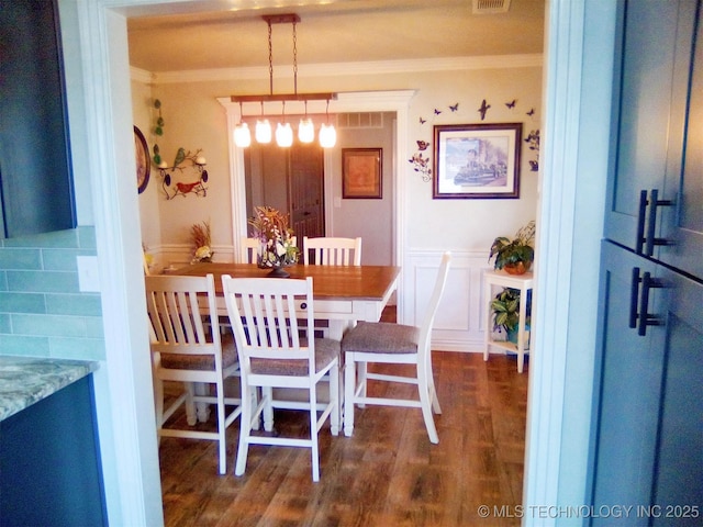 dining area with ornamental molding and dark hardwood / wood-style flooring