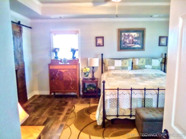 bedroom featuring crown molding, wood-type flooring, and a barn door