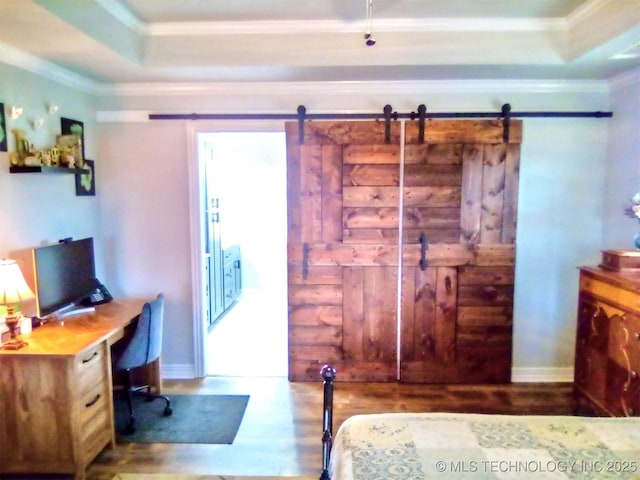 bedroom featuring hardwood / wood-style floors, ornamental molding, a barn door, and a raised ceiling