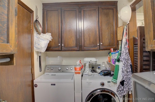 clothes washing area featuring cabinets and washer and clothes dryer