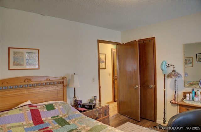 bedroom featuring light hardwood / wood-style floors and a textured ceiling