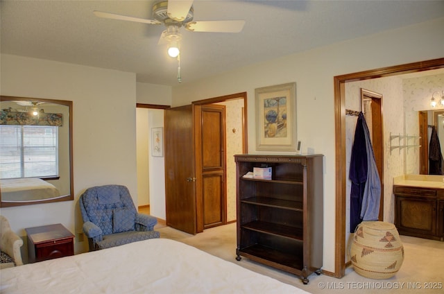 bedroom featuring ceiling fan, light colored carpet, and connected bathroom