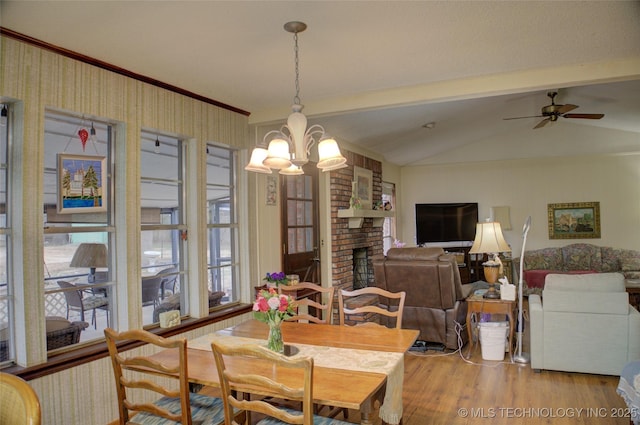 dining room with lofted ceiling, a fireplace, ornamental molding, light hardwood / wood-style floors, and ceiling fan with notable chandelier