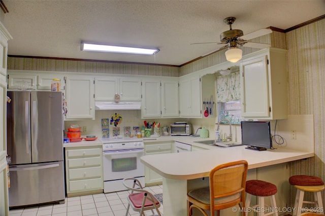 kitchen with white range with electric cooktop, stainless steel refrigerator, sink, a breakfast bar area, and kitchen peninsula