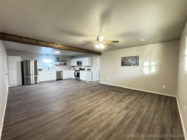 unfurnished living room featuring dark hardwood / wood-style flooring, beam ceiling, and ceiling fan