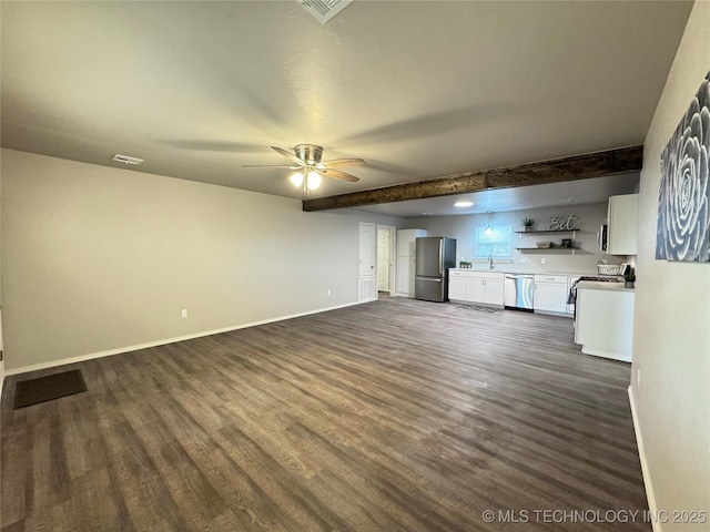 unfurnished living room featuring sink, beam ceiling, dark hardwood / wood-style floors, and ceiling fan