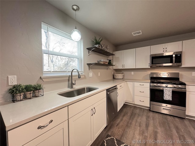 kitchen with appliances with stainless steel finishes, sink, hanging light fixtures, and white cabinets